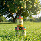 Jars of mango pickle on grass with a mango tree in the background