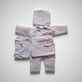 Traditional Nepali clothing set laid out on a surface, consisting of a pink and white checkered daura surwal, voto, and shoes for a newborn baby.