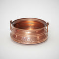 A copper khadkulo with embossed patterns and two handles.