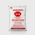 A 1 lb bag of Aji-No-Moto Umami Seasoning Monosodium Glutamate, in a clear plastic bag showing the white seasoning powder inside, with red and black text and logo on a light gray background.