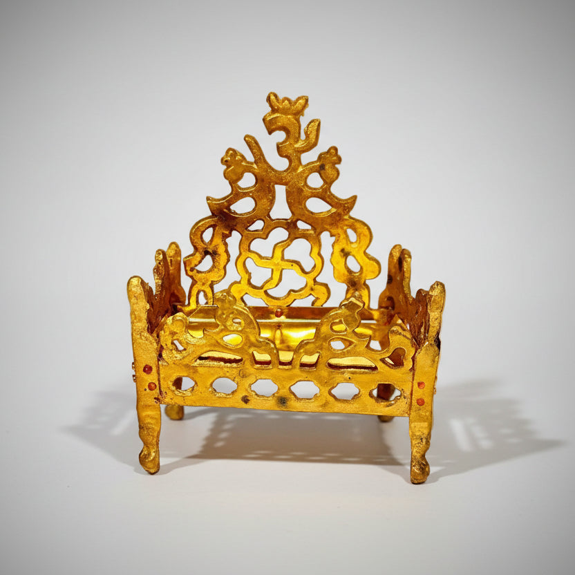 A decorative golden structure, possibly a miniature temple or a stand with intricate designs and a symbol at the top.