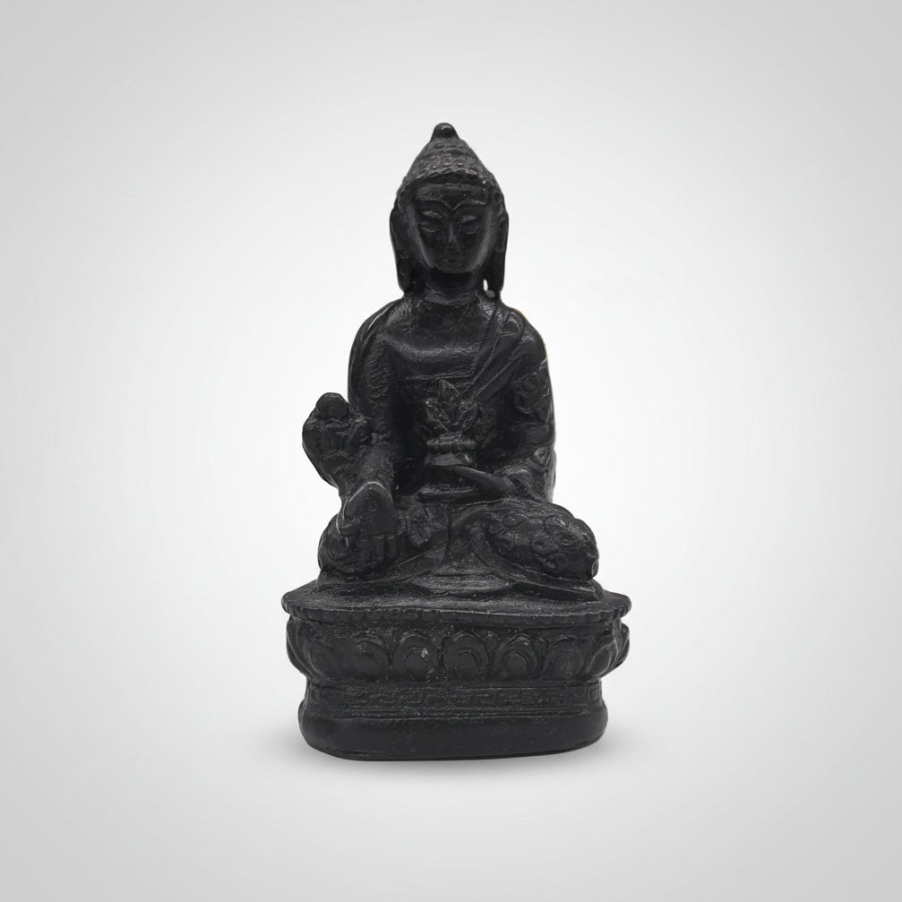 Small black Buddha statue on a white surface with blurred background