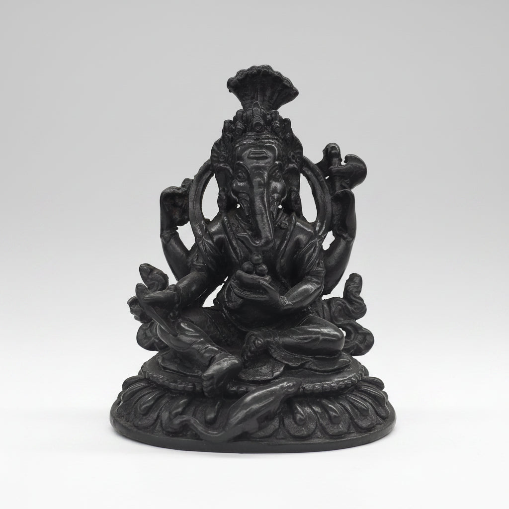 Black metal statue of a seated figure with a headdress on a white background