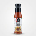 A bottle of Chettinad Red Chilli Sauce lying horizontally on a light-colored surface, with a blurred store background showing shelves and items.