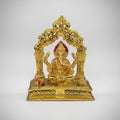 Gold-colored decorative statue on a white surface with blurred shelves in the background
