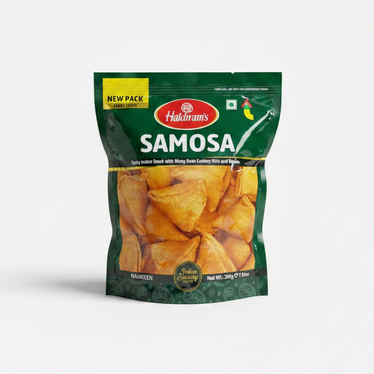 A packaged product of Haldiram Samosa, showing the snacks inside a transparent window on the packaging. The bag is green and yellow with branding and product name.