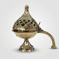 An ornate brass incense burner with a perforated lid, pedestal base, and curved handle, shown on a plain light gray background.