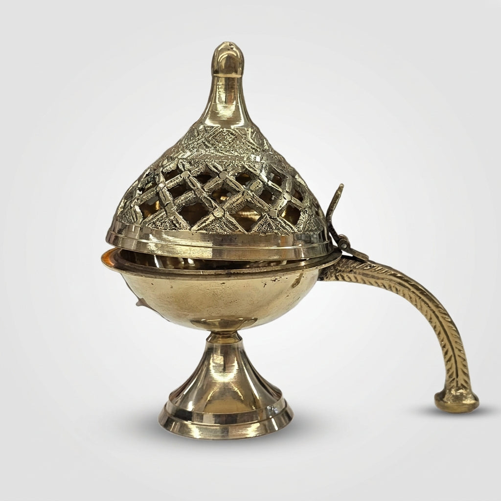 An ornate brass incense burner with a perforated lid, pedestal base, and curved handle, shown on a plain light gray background.