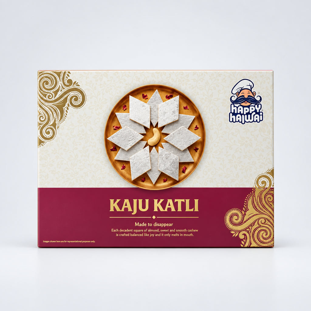 A boxed food product labeled 'KAJU KATLI' with a large photo of the prepared dish on the front, photographed on a white tabletop in a store setting. The box is cream and burgundy with ornate gold decorative swirls and a 'happy hajwa!' logo.
