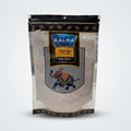 A stand-up pouch of Kalra Black Salt (Royal Meals) sitting on a white counter in a grocery store aisle. The packaging features a black top and bottom border, a blue and gold central logo, and an illustration of an elephant carrying a mace.