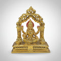 Gold-colored deity statue on a white surface with blurred colorful background