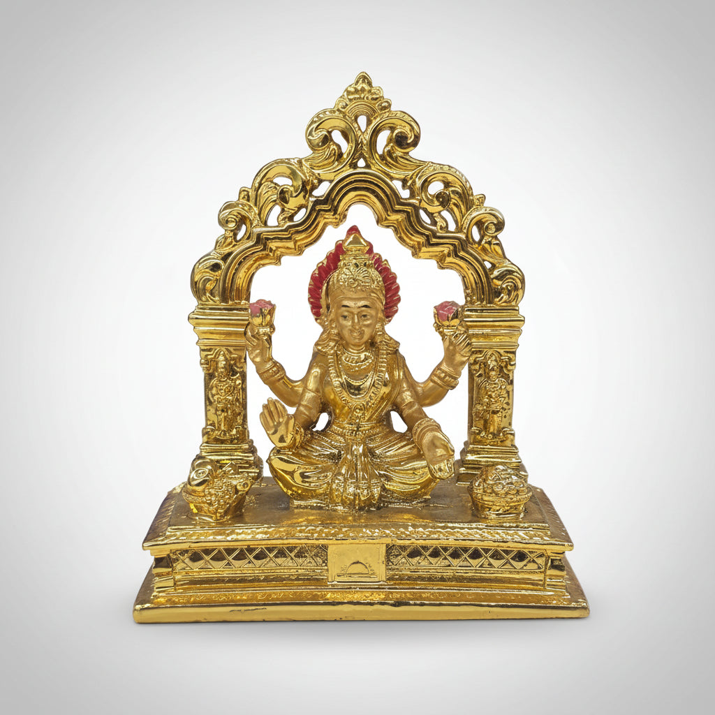 Gold-colored deity statue on a white surface with blurred colorful background