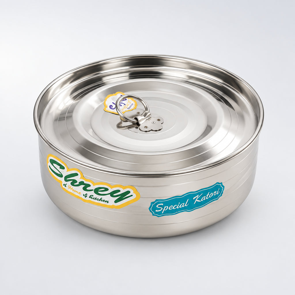 A small silver steel masala box with a lid, placed on a white surface, with a small plant pot and a toy visible in the background.