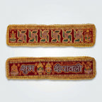 Three red and gold embroidered Diwali banners with Devanagari text and festive motifs, arranged on a decorated table with lit oil lamps, petals, and rangoli in the background.
