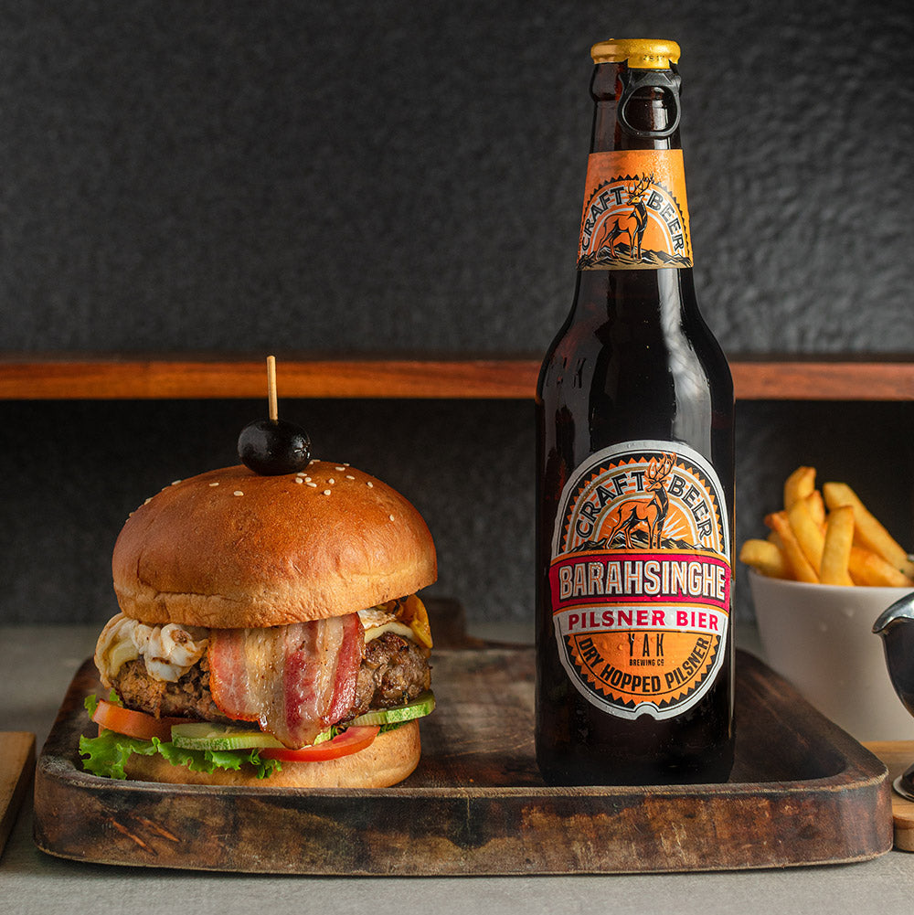 Burger and bottle of beer on a wooden tray with a dark background