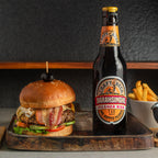 Burger and bottle of beer on a wooden tray with a dark background