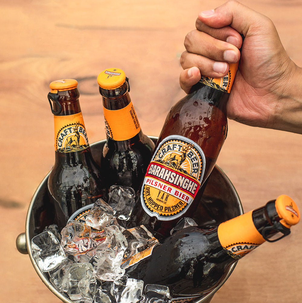 Three bottles of Mahb Singh beer in a bucket of ice, with a hand holding one bottle.