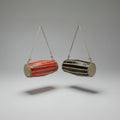 A traditional red hand drum (Madal) with a cylindrical shape, suspended by a strap against a white background.