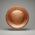 A decorative copper tray with embossed patterns displayed against a white background.