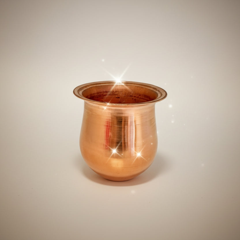 A small, cylindrical, copper-colored pot placed on a white surface, likely a cooking utensil.