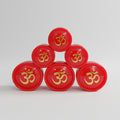 Five small red containers of Sindur powder arranged in a triangular formation on a light background, each with a golden design that resembles a OM symbol in the center.