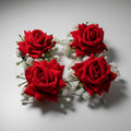Four red rose hair clips with green leaves and white accents, displayed on a white background