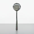 Metallic ladle with perforated spoon head on a white background