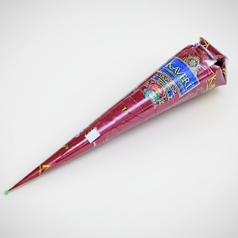 A cone-shaped container of mehendi (henna) with a decorative pattern, predominantly red with gold accents, used for body painting.