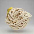A coiled beige rope made of cotton, with a visible yellow label indicating the brand or manufacturer.