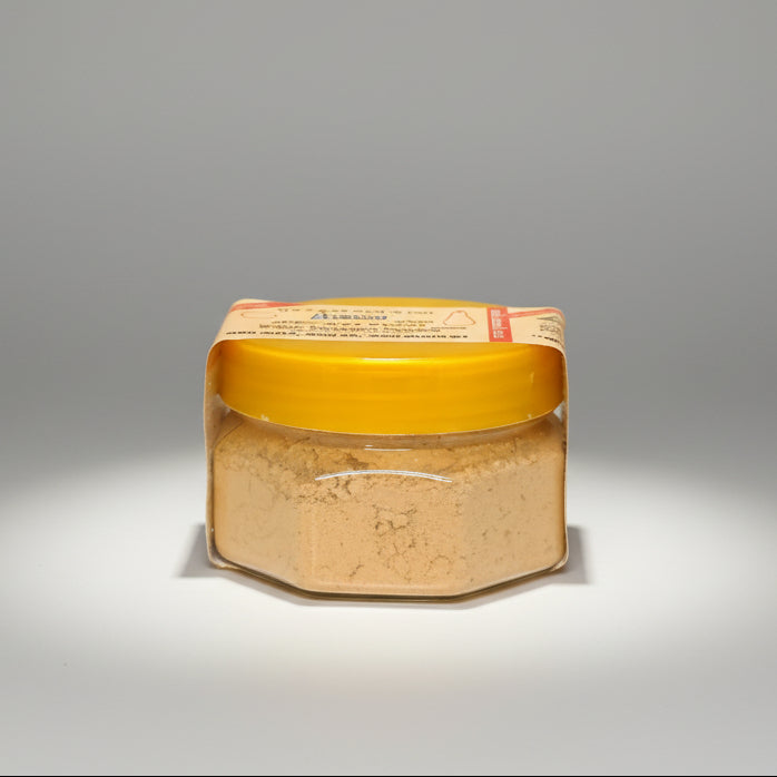 A plastic jar containing Chandan powder, with a yellow lid, against a light background.