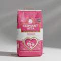 A 10kg bag of Elephant Atta medium Chapatti flour, predominantly pink in color with a white and gold heart shape design featuring an elephant.