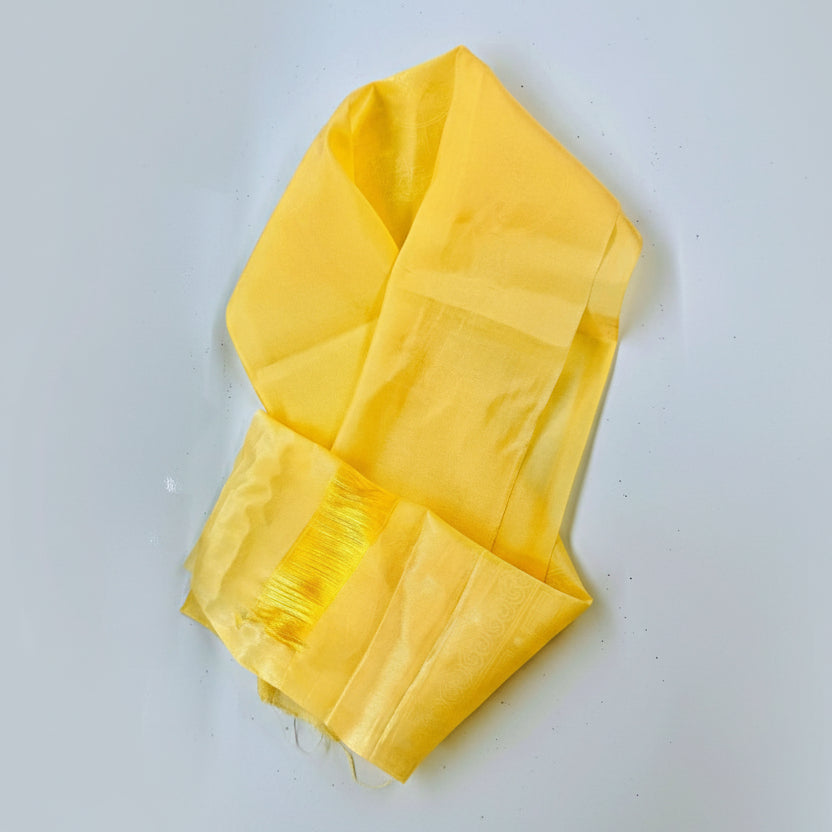 A yellow traditional fabric accessory, possibly a khada, laid flat with a visible fringed end.