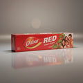 Dabur Red toothpaste box on a reflective surface with a gray background