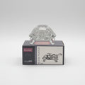 Glass turtle figurine with packaging on a white surface, blurred bookshelf in the background